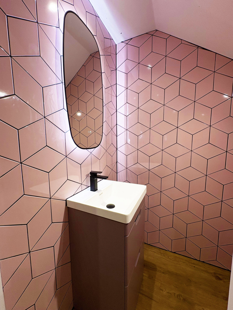 A stylish bathroom adorned with pink tiles and a sleek basin, offering a fresh and inviting look.