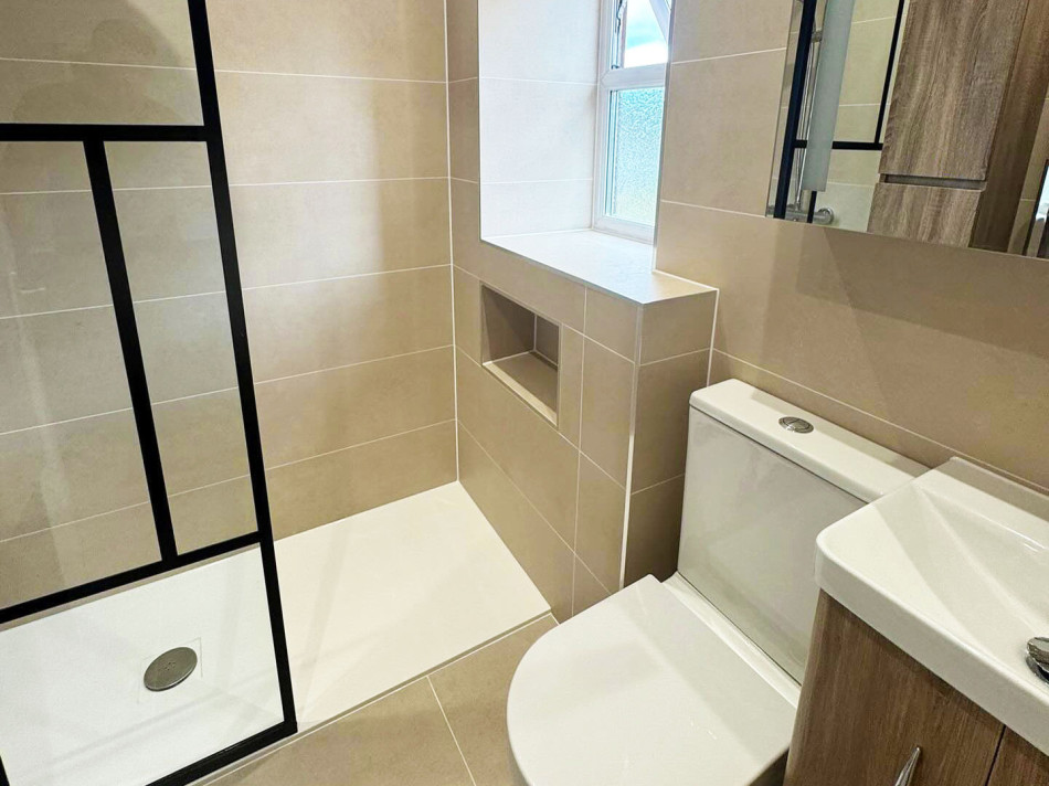 A modern bathroom featuring a toilet, basin, and a spacious shower area.