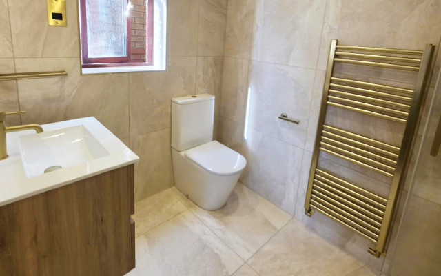 A modern bathroom featuring a toilet, basin, and a towel rack against a stylish tiled wall.