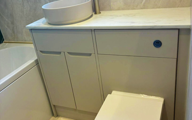 A clean bathroom featuring a modern toilet, basin, and bath arranged for easy access and comfort.