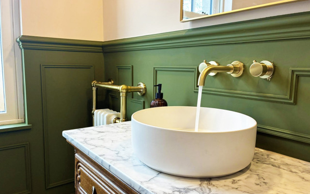A stylish bathroom with vibrant green walls and an elegant marble basin, enhancing the space's contemporary design.