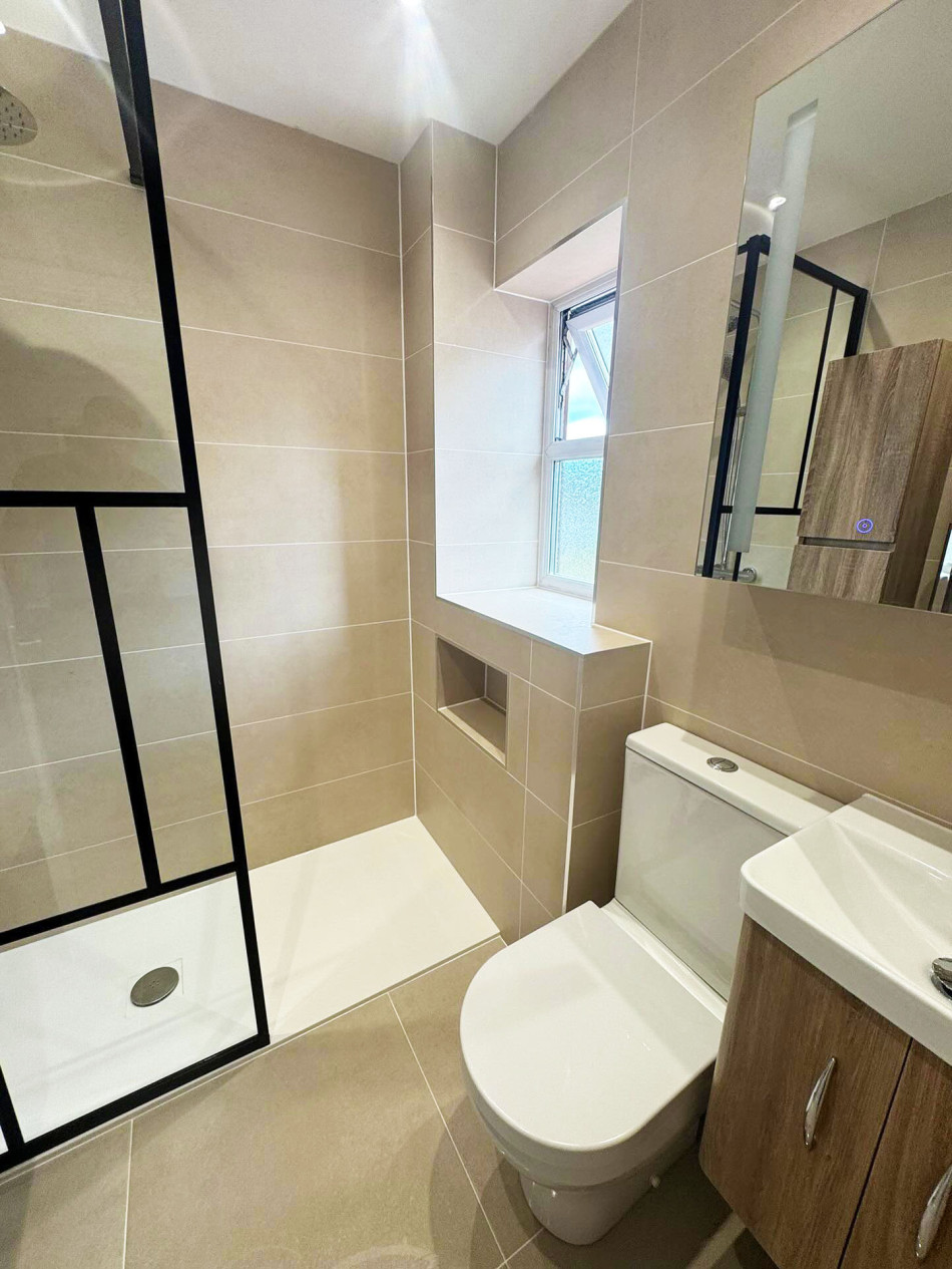 A modern bathroom featuring a toilet, basin, and a spacious shower area.