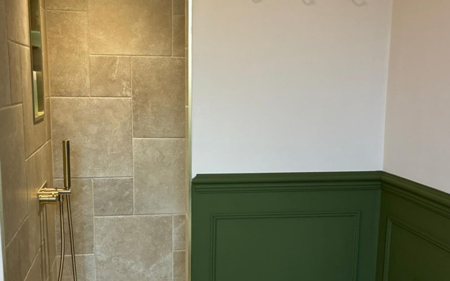 A modern bathroom featuring sleek tile work and elegant green paneling, creating a fresh and inviting atmosphere.