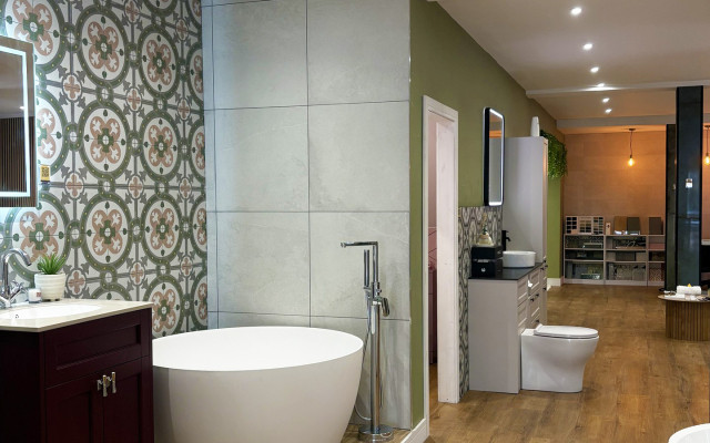 A stylish bathroom showroom with green and white tile walls and a bathtub.