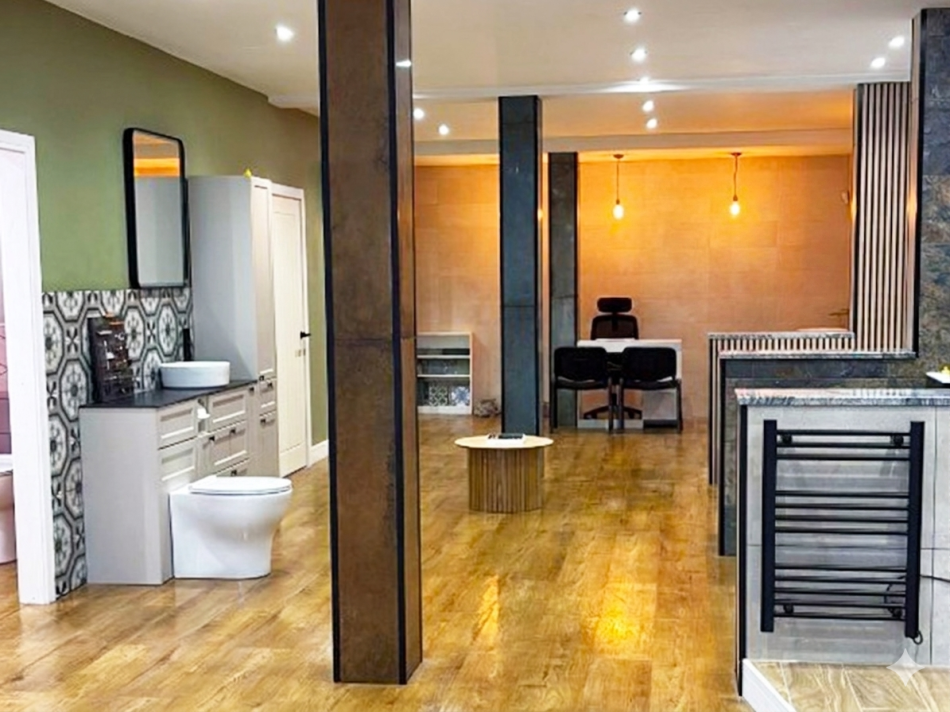 Bathroom showroom featuring a stylish basin, toilet, countertop, and modern decor with wooden flooring.