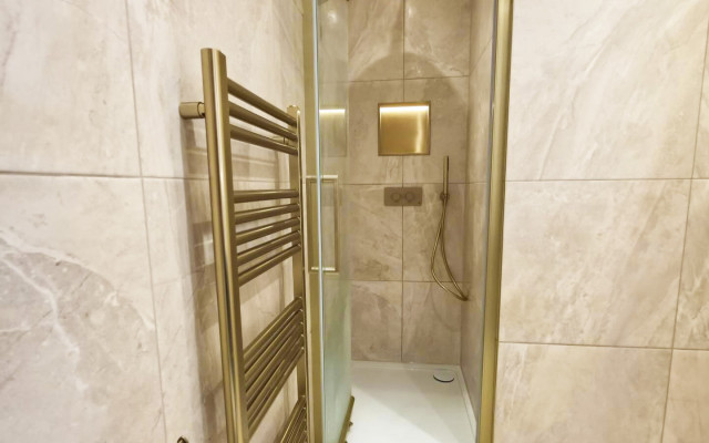 A modern bathroom featuring a stunning shower with an elegant gold towel rack, creating a luxurious atmosphere against a stylish neutral backdrop.