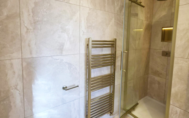 A modern shower featuring a sleek glass door and a stylish towel rack for added convenience, ideal for contemporary bathroom designs.